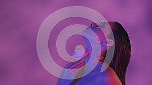 Close up video of a young woman touching her neck and shoulders with a pink rose in blue and pink color scheme and