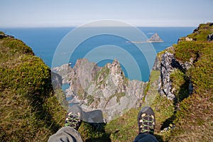 Man sitting on the edge of a cliff. The view of the feet in sports shoes is necessary to the abyss overlooking the rocks and the