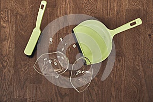 A close-up view from above of a split transparent cup with soup and brushes with a dustpan for cleaning. The concept of