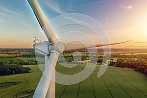 Close up view from above of a wind turbine for renewable green electricity with green rural landscape, silos on the background.