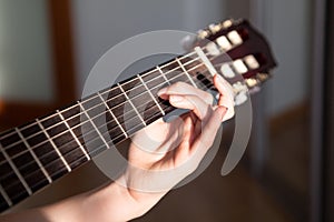 Close up view at acoustic guitar fretboard with female hand striking a chord