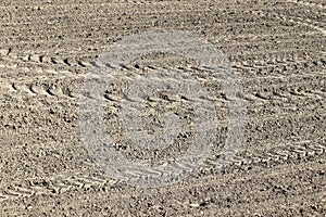 Close up view on agricultural fields with dry ground and tractor tracks