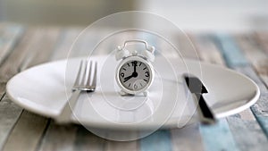 Close up view of alarm clock on a plate intermittent fasting diet concept , time to eat healthy lifestyle