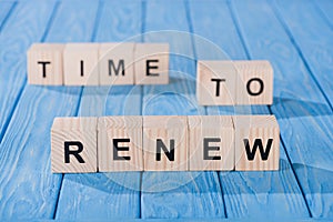 close up view of arranged wooden blocks into time to renew phrase on blue