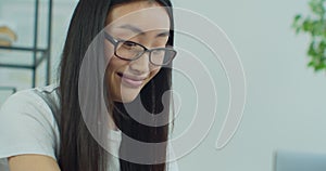 Close up view of Asian woman eyes with glasses freelancer works in home on laptop. Happy girl use computer for study