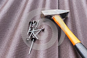 Close up view on asphalt roofing shingles background with hammer and nails