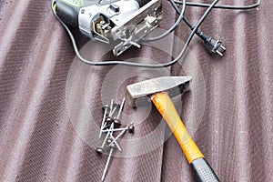 Close up view on asphalt roofing shingles background with hammer and nails