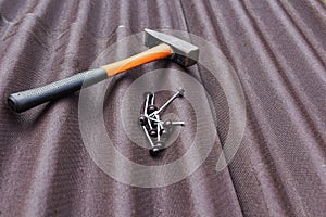 Close up view on asphalt roofing shingles background with hammer and nails