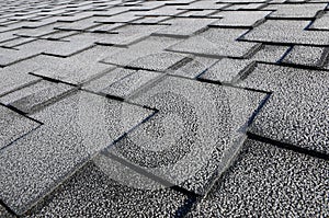 Close up view on Asphalt Roofing Shingles Background. Roof Shingles - Roofing. Roof shingles covered with frost