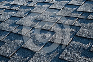 Close up view on asphalt roofing shingles covered with frost.