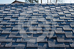 Close up view on asphalt roofing shingles covered with frost.