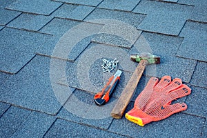 Close up view on asphalt shingles on a roof with hammer,nails and stationery knife.