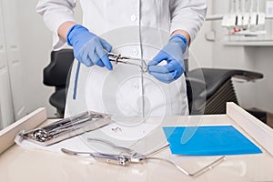 Close-up view of assistant`s hands with blue gloves working with dental tools