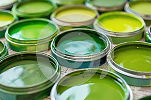 Close-up view of assorted green paint cans showing various shades and tints for artistic and decor use photo