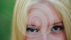 Close-up view of attractive face and stunning blue eyes of charming young caucasian blond woman with graceful and