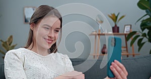 Close up view of attractive woman showing with with deaf-mute sign language phrase I miss you while sitting on sofa
