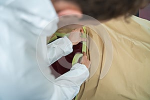 Close-up view of auto painter`s who covering a car body before painting with masking tape and paper.