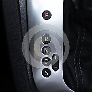 Close-up view of automatic gearbox selector on black background.