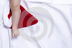 Close-up view of baby boy`s legs on red Santa Claus hat. First Christmas of a newborn baby