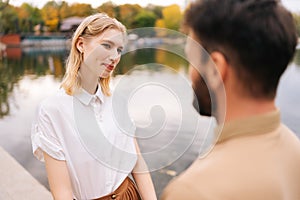 Close up view from back of unrecognizable bearded man to cheerful woman standing holding hands with boyfriend outdoors