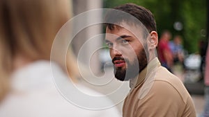 Close-up view from back of unrecognizable blonde young woman to handsome bearded man smiling talking with loving