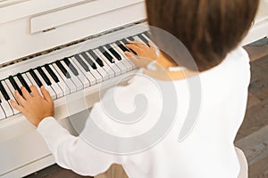 Close-up view from back of unrecognizable female musician performer playing on classical piano at home enjoying virtuoso