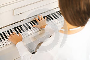 Close-up view from back of unrecognizable female pianist playing on classical piano at home enjoying virtuoso music in