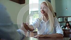 Close-up view from back of unrecognizable male of young business woman discussing project with coworker in cafe sitting