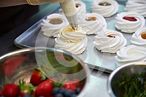 Close-up view baker decorating merengue nest with sweet whipped cream photo