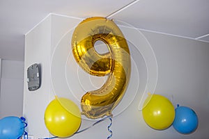 Close-up view of a balloon shaped like the number nine, used to celebrate a child\'s birthday.