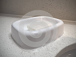 Close up view of a bar of white soap in a dish inside a clean bathroom