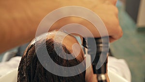 Close-up view of barber washing hair to male client