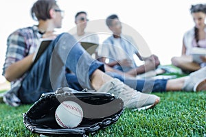 close-up view of baseball glove with ball and teenagers studying