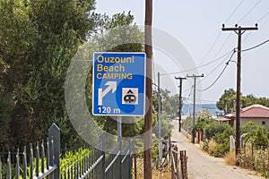 Close up view of beach camping road sign on village landscape background. Greece.