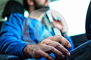 Close-up view of a bearded man that holds a gear while driving. Narrow focused on hand holding shift lever or gear level