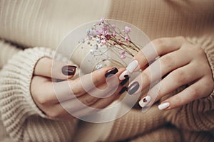 Close up view of beautiful female hand with fashion manicure nails, white and dark red gel polish