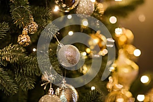 Close up view of beautiful fir branches with shiny golden bauble or ball, xmas ornaments and lights, Christmas holidays