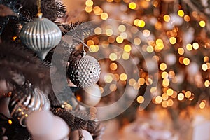 Close up view of beautiful fir branches with shiny golden bauble or ball, xmas ornaments and lights, Christmas holidays