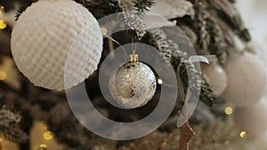 Close up view of beautiful fir branches with shiny white baubles or balls, golden xmas ornaments and lights. Holidays