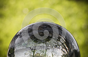 Close up view on beautiful landscape trees in blue sky and green meadow through lens ball sphere, france