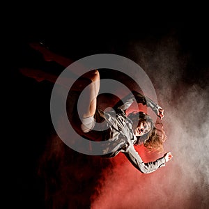 Close-up view of beautiful woman bouncing and performs trick in the air at dark time
