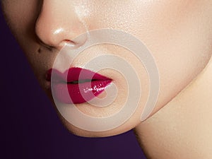 Close up view of beautiful woman lips with purple matte lipstick. Cosmetology, drugstore or fashion makeup