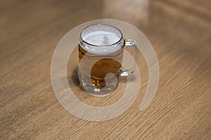 Close-up view of a beer mug filled with beer standing alone on a wooden table