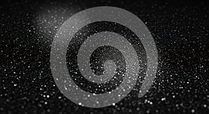 A close-up view of a black surface covered with shimmering particles, creating a