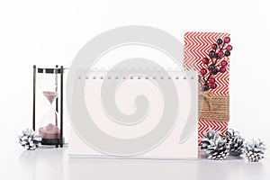 close up view of blank calendar, sand clock, pine cones and wrapped gift