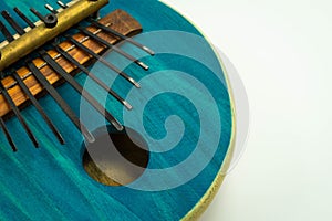 Close-up view of blue African kalimba made of pumpkin, on a white background with a small gap on the right. Traditional music