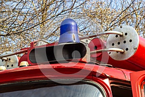 Close-up view of a blue light and fire hose on the roof of an antique fire engine