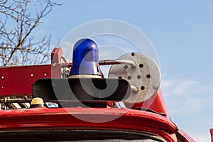 Close-up view of a blue light and fire hose on the roof of an antique fire engine