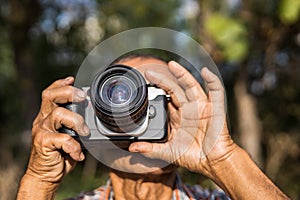 Close-up view of both hands of an elderly Thai man holding a film camera