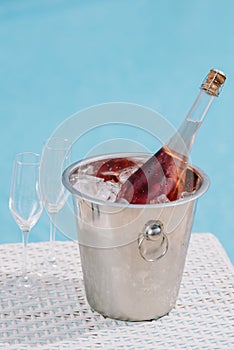 close-up view of bottle of champagne in bucket with ice and two empty glasses